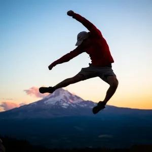 Energy Boost - man leaping into air in front of mountain