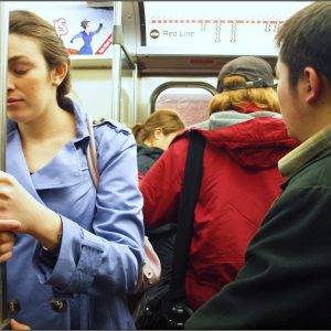 Woman holding bar in subway car looking nauseous