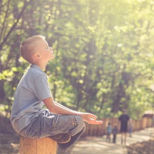 Boy sitting in sunlight with eyes closed