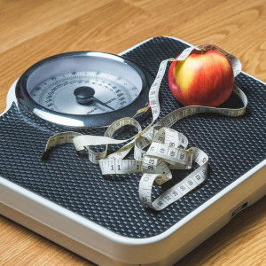 Weight loss - a scale with an apple and measuring tape on top