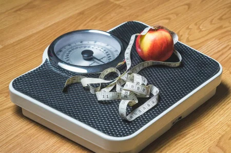 Weight loss - a scale with an apple and measuring tape on top